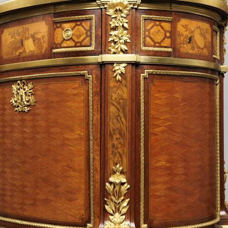 Close up detail of gilded marquetry on the corner of a curved piece of furniture