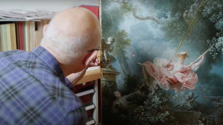 An image of a man conserving a painting