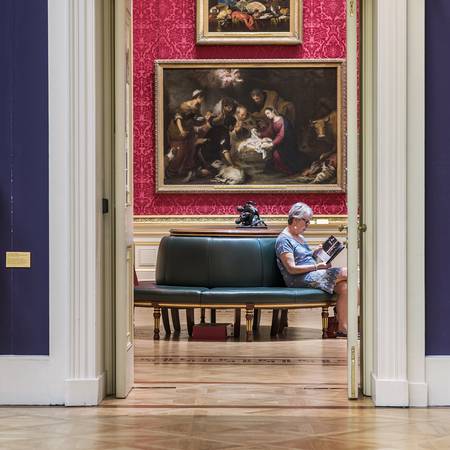 An image of a woman sat in the Great Gallery of the Wallace Collection