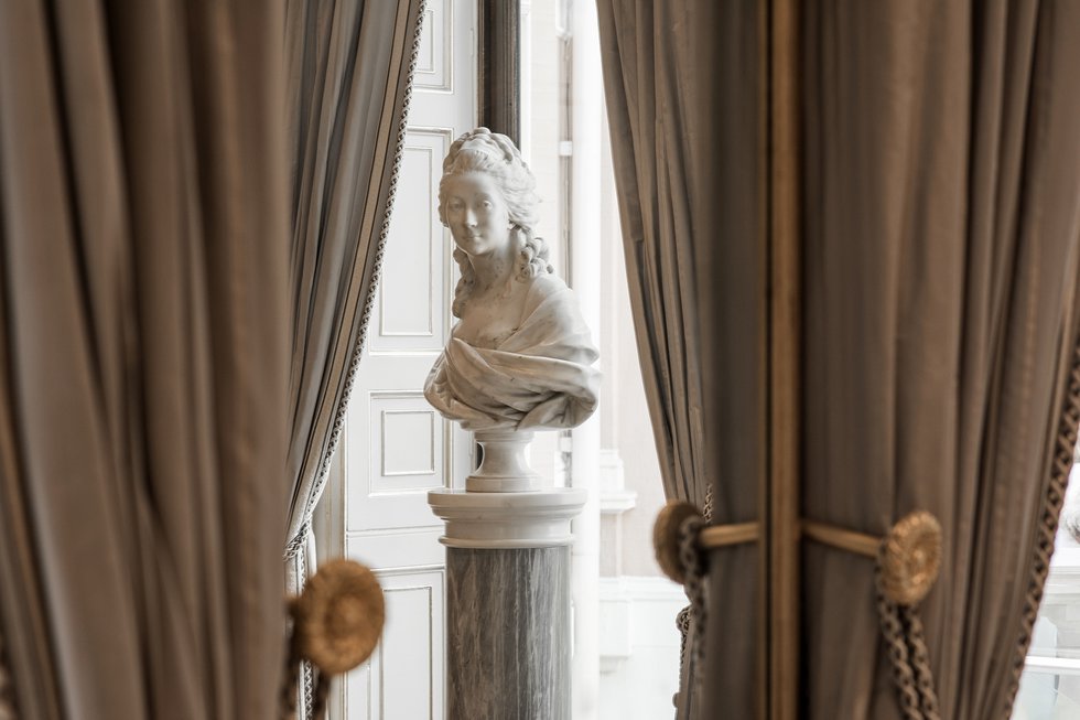 Bust of women reflected in mirror between curtains